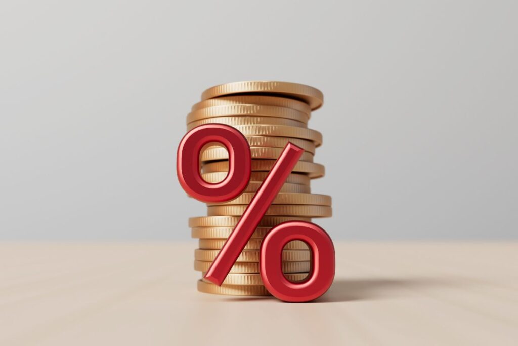 Uma pilha de moedas de ouro com um grande símbolo de porcentagem em vermelho, representando o aumento de comissões na Hotmart.
