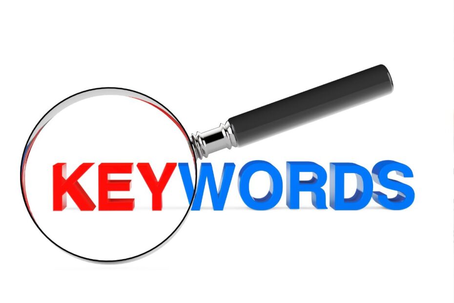 Lupa ampliando a palavra KEYWORDS em destaque vermelho e azul, representando ferramentas de pesquisa de palavras-chave para marketing de afiliados