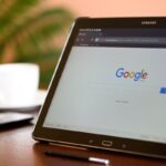 Tablet em ambiente de escritório ou cafeteria com a página do Google aberta. A imagem simboliza a busca por conhecimento e a otimização de páginas para conteúdo útil.