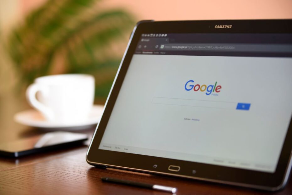 Tablet em ambiente de escritório ou cafeteria com a página do Google aberta. A imagem simboliza a busca por conhecimento e a otimização de páginas para conteúdo útil.