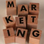 Blocos de madeira formando a palavra "MARKETING" representando a realidade dos negócios digitais e marketing de afiliados