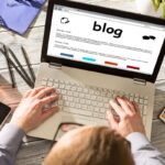 Visão aérea de uma pessoa usando ferramentas para blog em um computador.