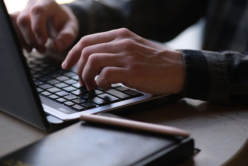 Mãos digitando no teclado, usando recursos e ferramentas de blog.