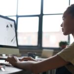 Jovem profissional resolvendo o problema de estruturar uma apresentação ao identificar e focar no tópico central na tela do computador.