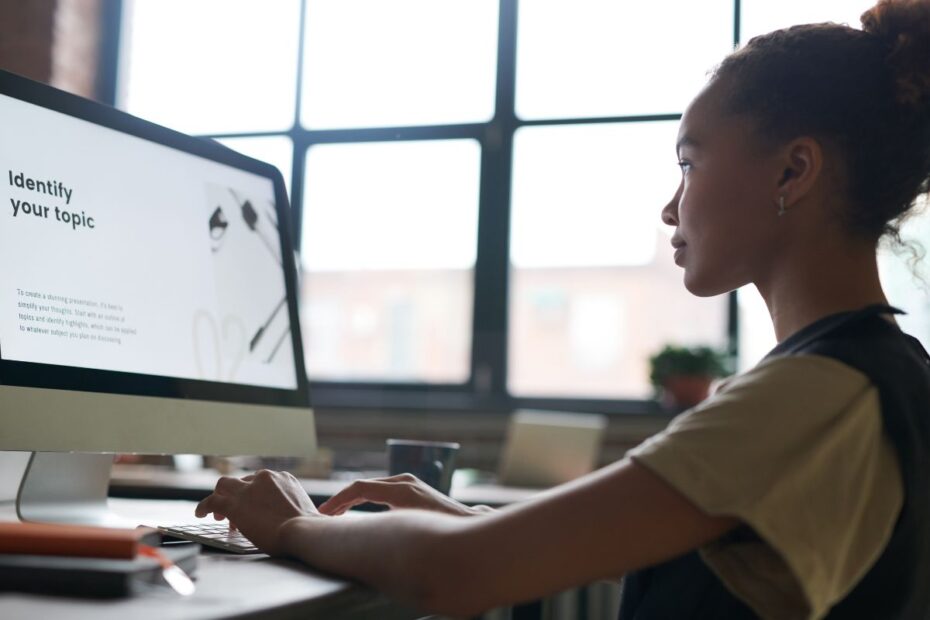 Jovem profissional resolvendo o problema de estruturar uma apresentação ao identificar e focar no tópico central na tela do computador.