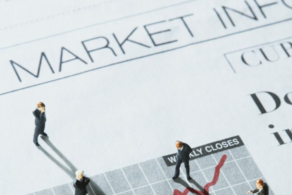Miniaturas de executivos sobre página de jornal com palavra Marketing em destaque e gráfico financeiro representando estratégias de conteúdo e análise de resultados para afiliados