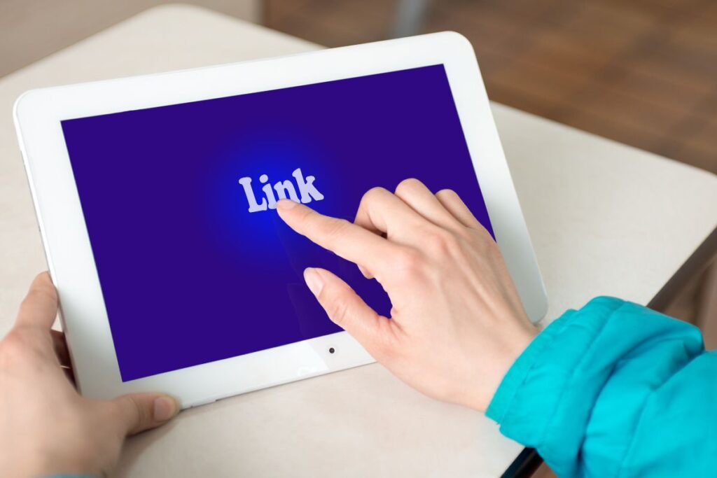 Pessoa tocando na palavra “Link” em um tablet, simbolizando o uso de link de afiliado para gerar renda online.