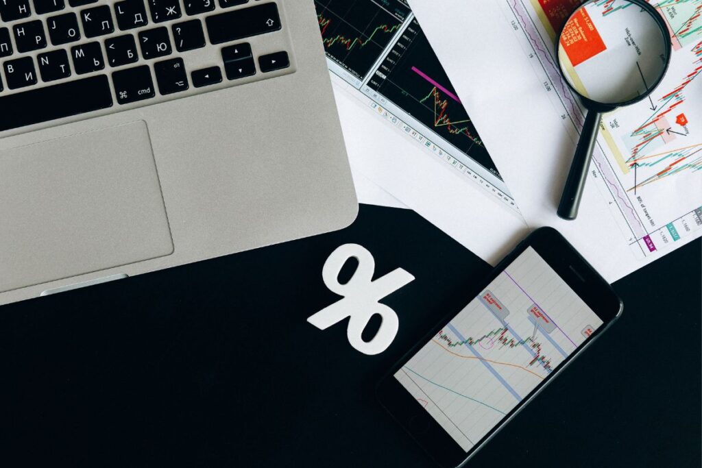 Símbolo de porcentagem ao lado de notebook e smartphone exibindo gráficos de análise de afiliados Awin.