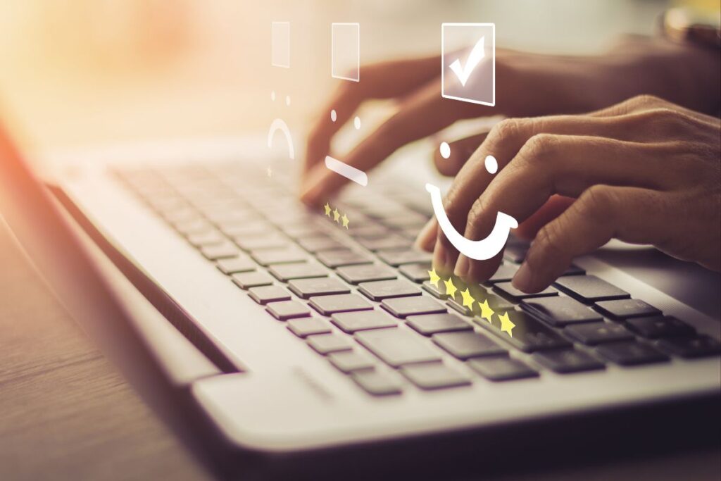 Pessoa digitando em laptop com ícones de avaliação e estrelas representando feedback positivo sobre digitais para afiliados